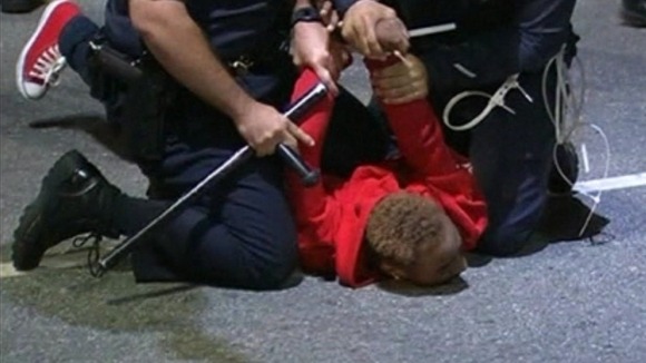 Police officers hold a man on the ground at one of the protests in Los Angeles