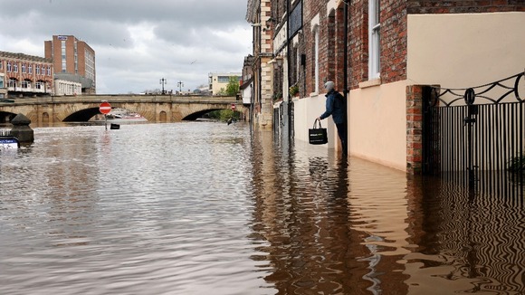 A woman stands on a step as she makes her way along a flooded street in York after the River Ouse flooded parts of the city.