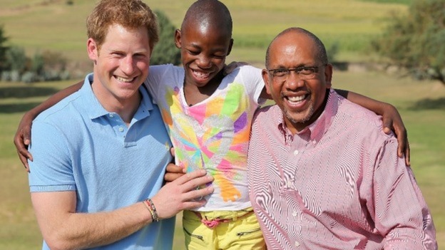Prince Harry poses with Prince Seeiso of Lesotho and a child that has been helped by their charity.