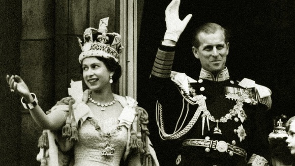 The Queen wearing the Imperial State Crown and the Duke of Edinburgh in uniform on the balcony.