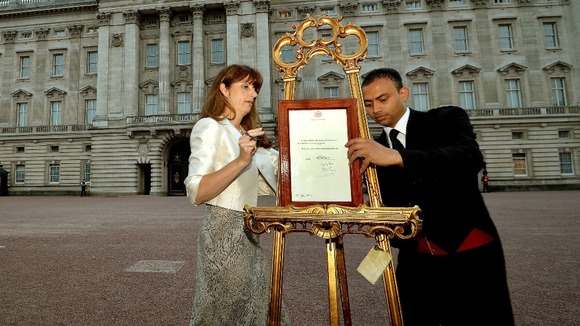 Queen's Press Secretary Ailsa Anderson and footman Badar Azim placing the royal baby birth notification onto an easel.