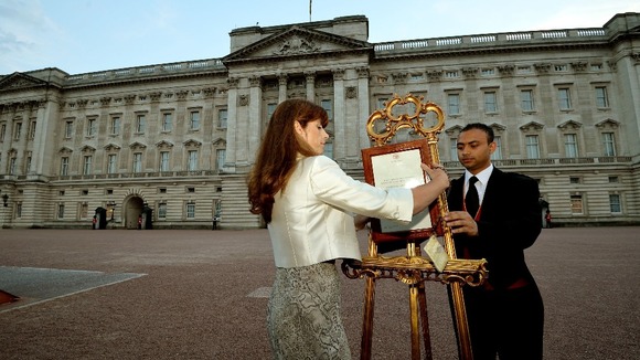 The Queen's Press Secretary Ailsa Anderson and footman Badar Azim posting the royal baby birth notification in front of Buckingham Palace.
