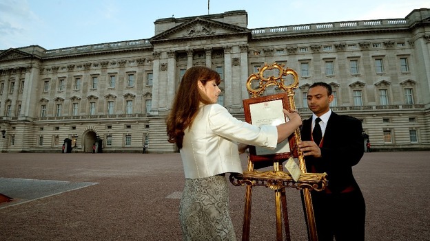 The Queen's Press Secretary Ailsa Anderson and footman Badar Azim posting the royal baby birth notification in front of Buckingham Palace.