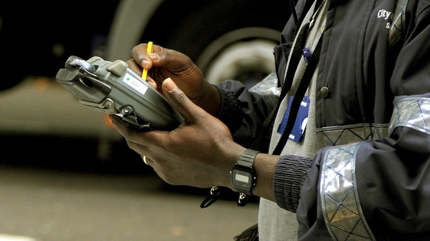 A civil enforcement officer issues a parking ticket in London.