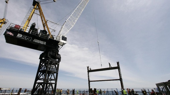Crane on the top deck of One world Trade Center holds a steel beam between two columns to make the tower New York City's tallest skyscraper