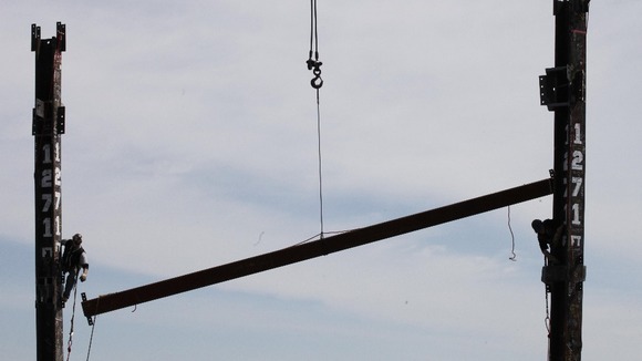 Workers release steel cable after connecting steel beam between two columns at top of World Trade Center making it NYC's tallest building