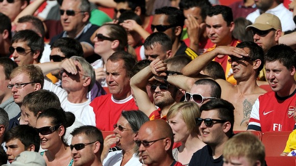 A packed stand at the Emirates Stadium as football fans enjoy the game in the sun.