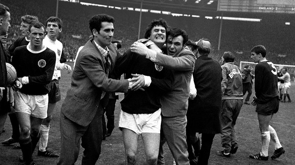 Scotland's Jim Baxter is enthusiastically hugged by overjoyed fans