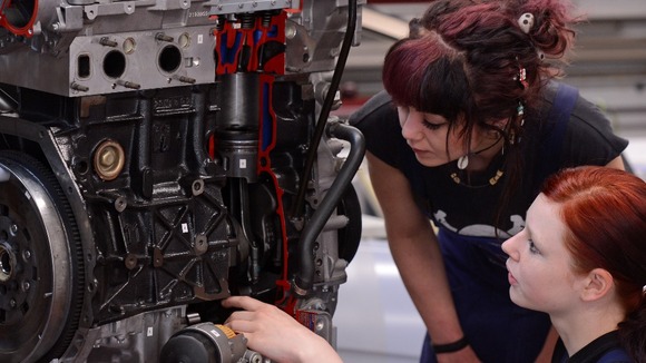 Apprentices study a cutaway model of a car engine