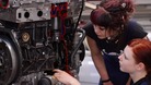 Apprentices study a cutaway model of a car engine