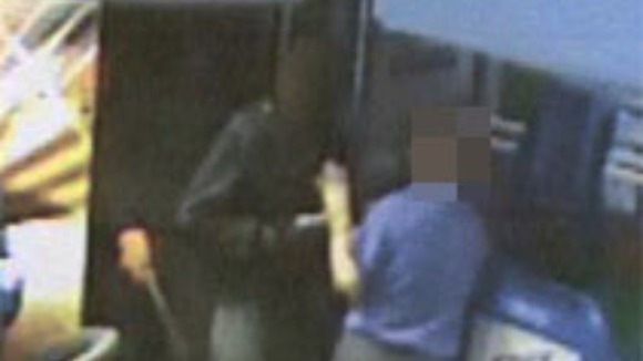 Masked man threatening a staff member with a handgun.
