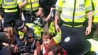 Caroline Lucas MP is seen in the centre wearing a red scarf surrounded by police