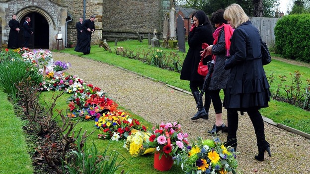 Mourners look at floral tributes as they attend the funeral of Claire Squires