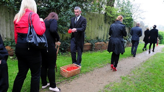 Mourners are handed red wristbands as they attend the funeral of Claire Squires at St Andrew's Church in North Kilworth