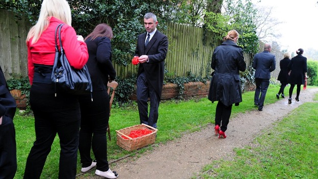 Mourners are handed red wristbands as they attend the funeral of Claire Squires at St Andrew's Church in North Kilworth