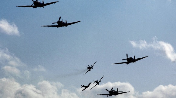 A group of eight Supermarine Spitfires fly above the Imperial War Museum airfield at Duxford.
