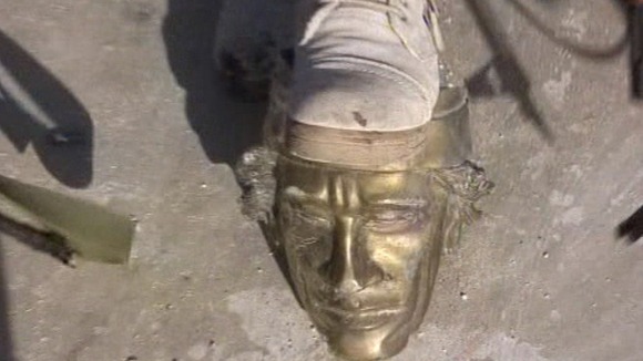 A rebel fighter rests his foot on a statue of Libya's dposed leader Muammar Gadaffi