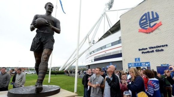 Fans look at the new Nat Lofthouse statue outside the Reebok Stadium