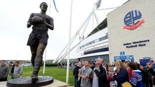 Fans look at the new Nat Lofthouse statue outside the Reebok Stadium