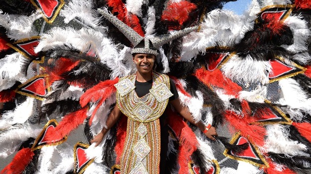 One entertainer wears an elaborate, richly-feathered costume