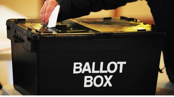 A voter places a ballot paper in the ballot box.