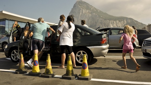 People stand outside their cars to cool down as they wait in queues on the Gibraltar side of the Spanish border