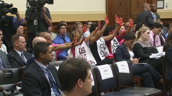 The demonstrators hold up their hands which are painted red.