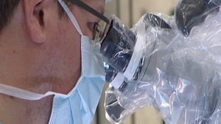 Surgeon looking into a microscope