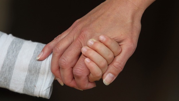 An adult holds hands with a child.