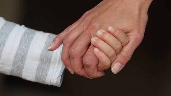 A child and an adult hold hands.