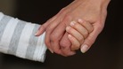 A child and an adult hold hands.