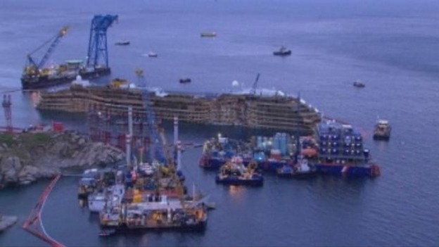 Engineering boats surround the cruise liner after the successful operation.