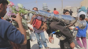 A street vendor pours a cup of coffee from a flask on his back at Zaatari refugee camp in Jordan
