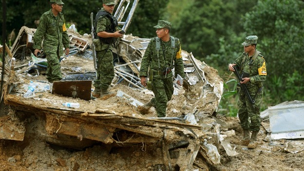 Soldiers stand on the remains of a bus after it was buried by a mountain landslide in Altotonga in Veracruz state.