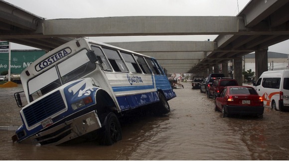 A stranded bus is seen as cars make their way through a flooded street in Acapulco.