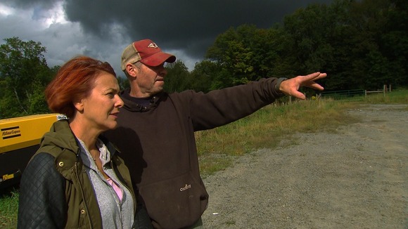 Man and lady in profile on farmland, man pointing