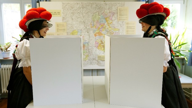 Corinna Woehrle and Gerlinde Moser (L) wearing traditional Black Forest costumes, fill ballots