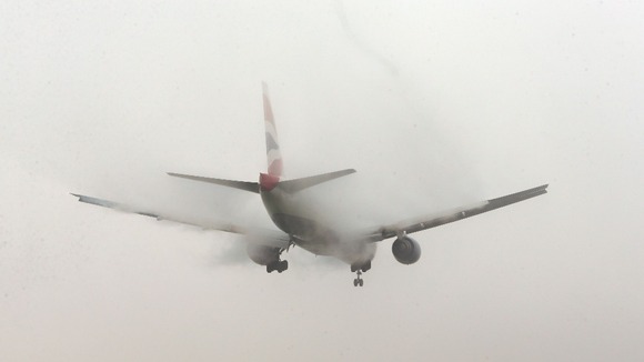 A British Airways planes lands in the fog at Heathrow Airport, London, this morning.