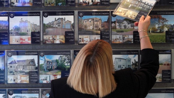 A woman looks at houses for sale in an estate agents.