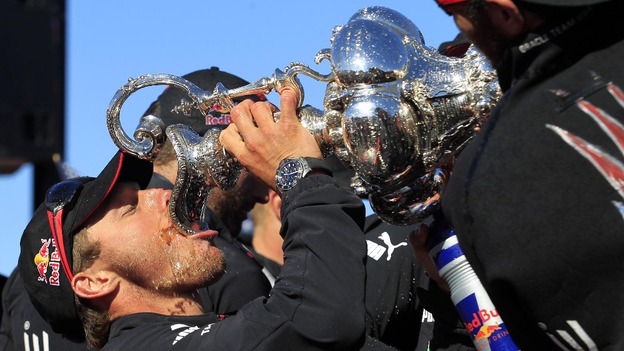 Oracle Team USA tactician Ben Ainslie drinks from the America's Cup trophy as he celebrates with crew members on Pier 27.