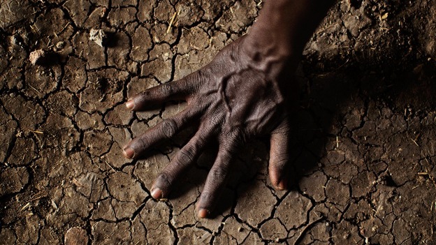 A man places his hand on the parched soil in the Greater Upper Nile region of northeastern South Sudan