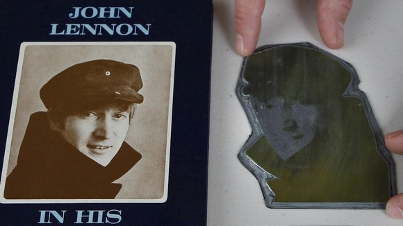Auctioneer Paul Fairweather positions an image on a printers plate of John Lennon