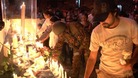A soldier lights a candle at a vigil for attack victims