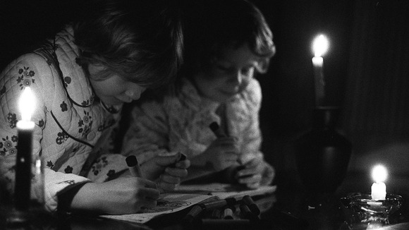 Image from 1977 of two children with candles in a blackout.