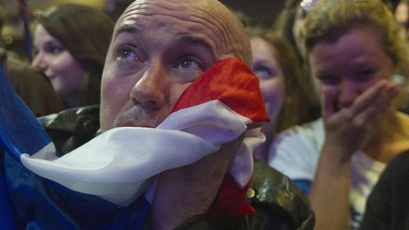 A supporter of outgoing French President Nicolas Sarkozy's covers his face with the national flag 