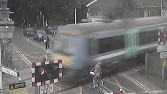 The woman encroaches onto the line just as the approaching train passes