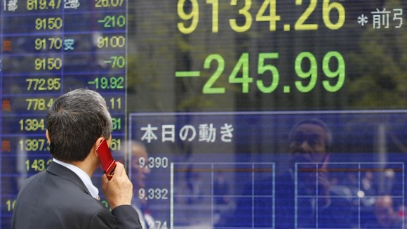 A man speaks on a mobile phone in front of a securities firm's electronic stock board in Tokyo