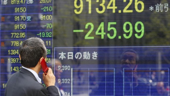 A man speaks on a mobile phone in front of a securities firm's electronic stock board in Tokyo