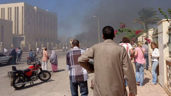 Residents and tourists watch smoke rising near a state security building in South Sinai.