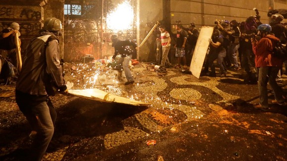 A protester hurls a petrol bomb at the gates of the Municipal Assembly in Rio de Janeiro, Brazil